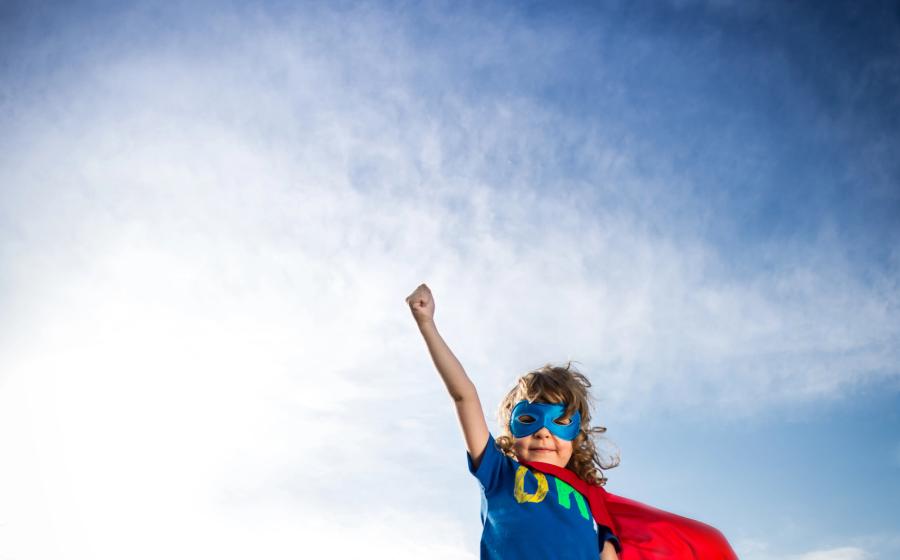 Young superhero girl against a blue and cloudy sky