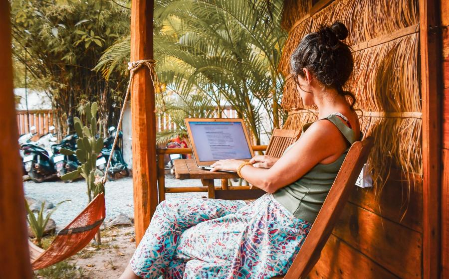 Close up young woman sitting at a table outside working on her computer