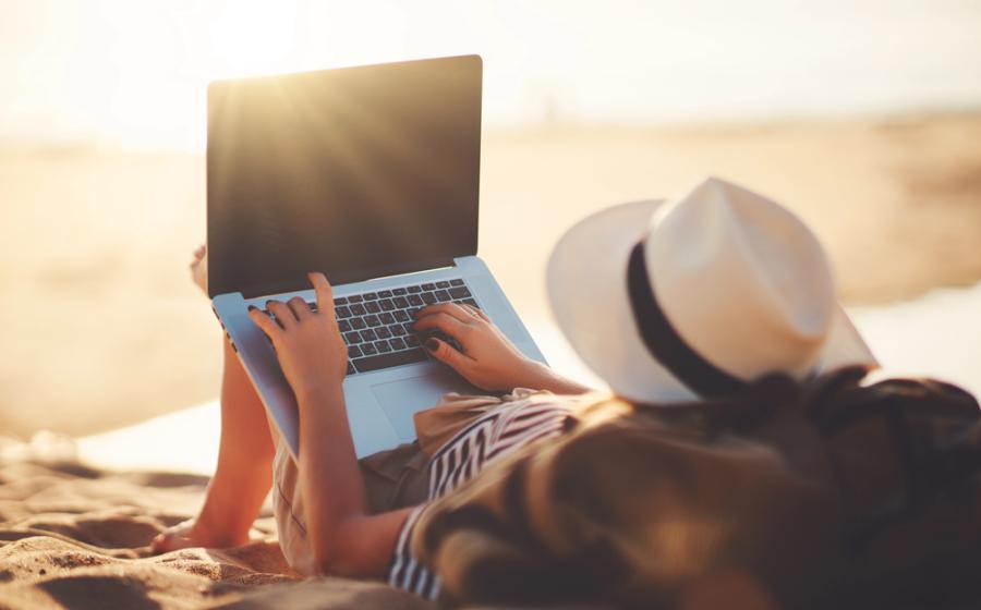 Young woman working with a laptop on nature in summer beach