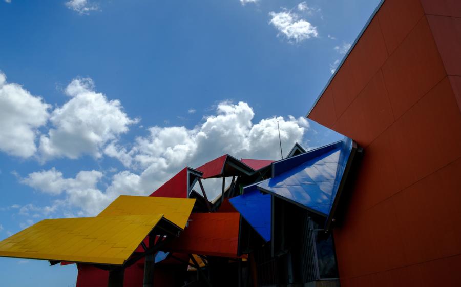 Roofline of the Biomuseo with colorful roofing, wall, and blue sky with clouds
