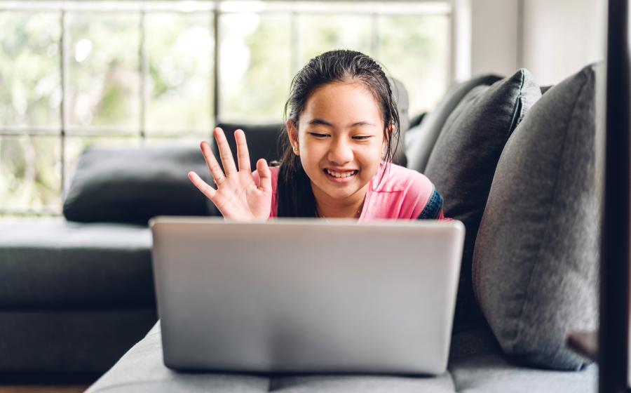 Young girl waving hello to her laptop