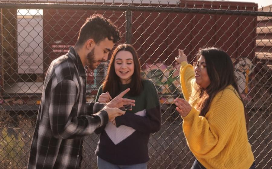 man and two women standing near linked-chain fence