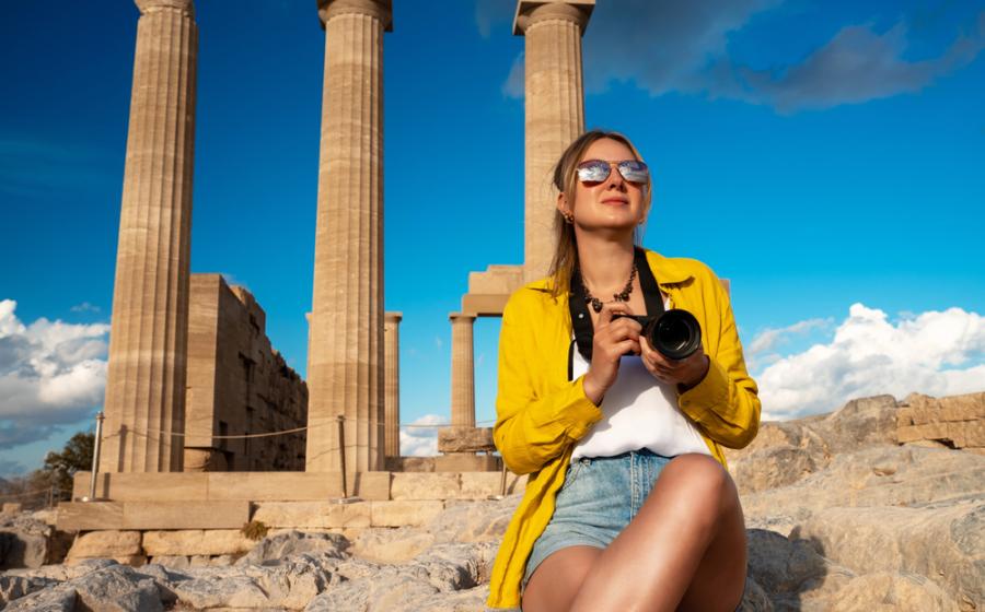 A woman tourist with a camera in the Acropolis on an excursion