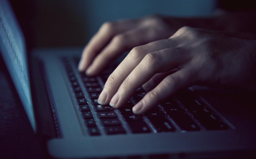 Hands with laptop typing in night