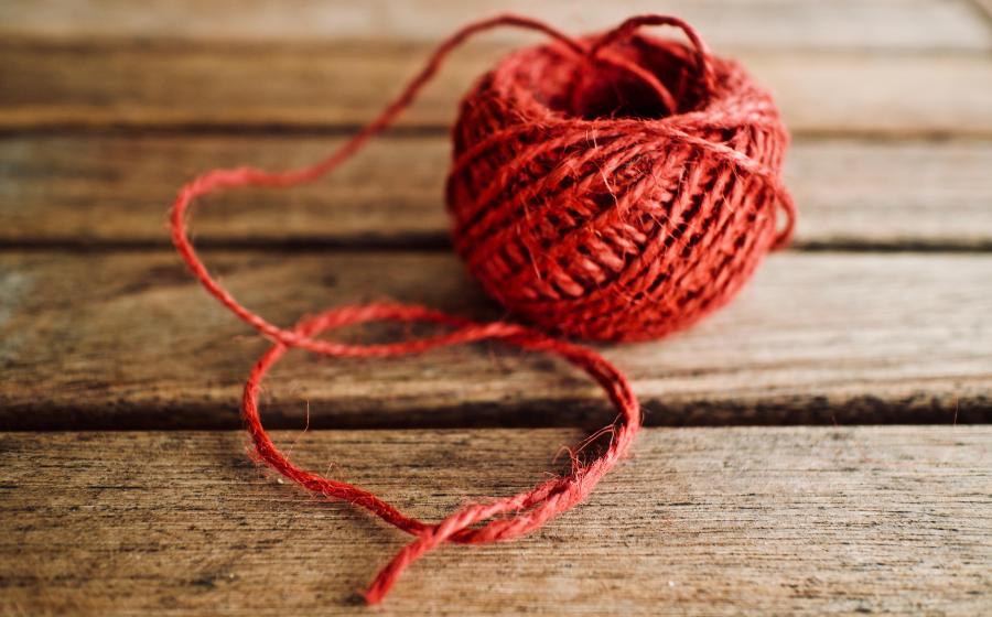 spool of red yarn on a wooden bench