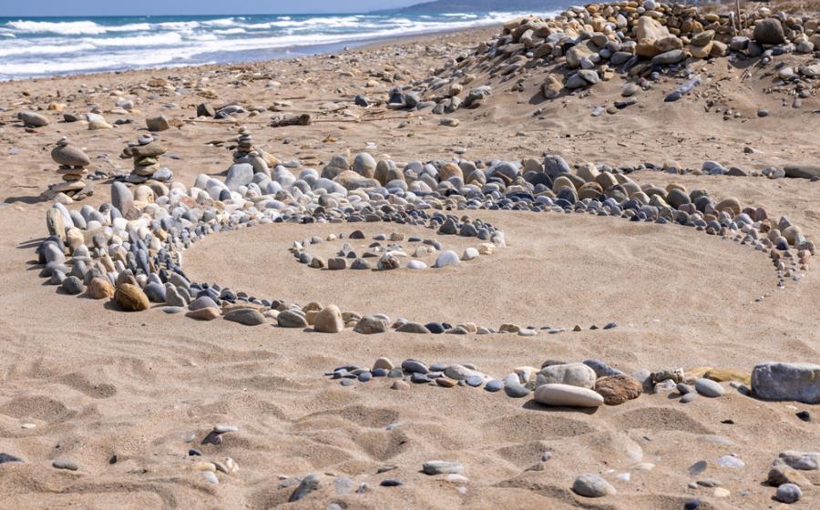 Snail made of stones in summer on the beach of Crete, Greece
