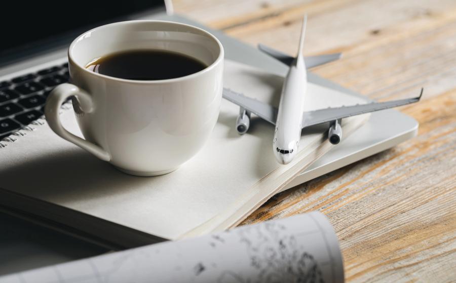 Coffee, notebook, and toy airplane sitting near a laptop