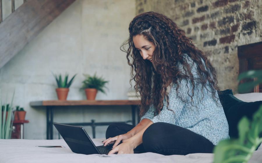 Woman with curly hair typing on a laptop