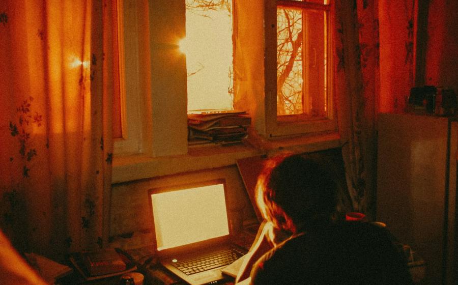 working on a computer with sun streaming in the window