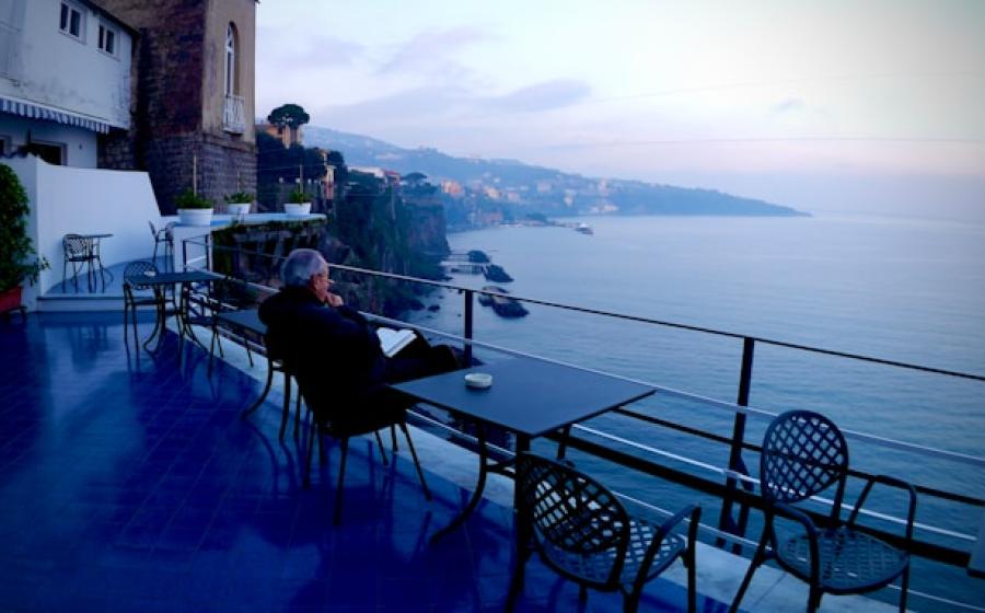 man in black jacket sitting on black chair near body of water during daytime