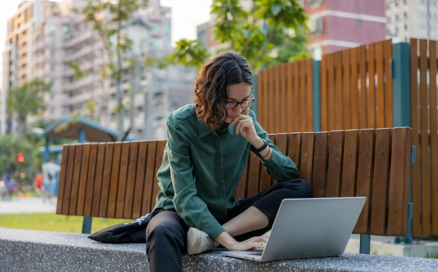 Woman using a laptop on a city bench
