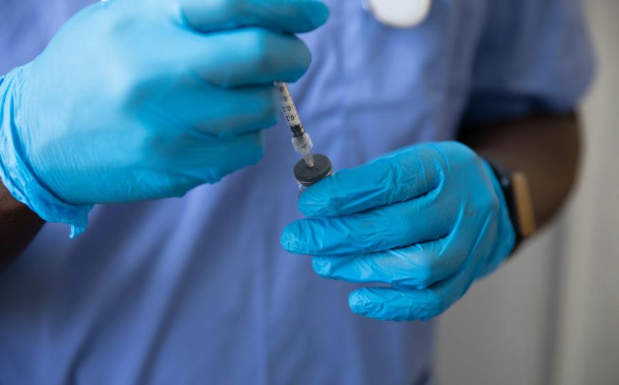Gloved medical professional giving a shot