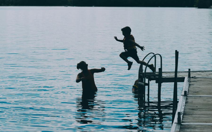 Kid jumping into the lake, parent watching