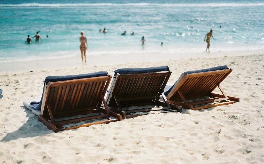 Loungers on the sand, bright blue water beyond
