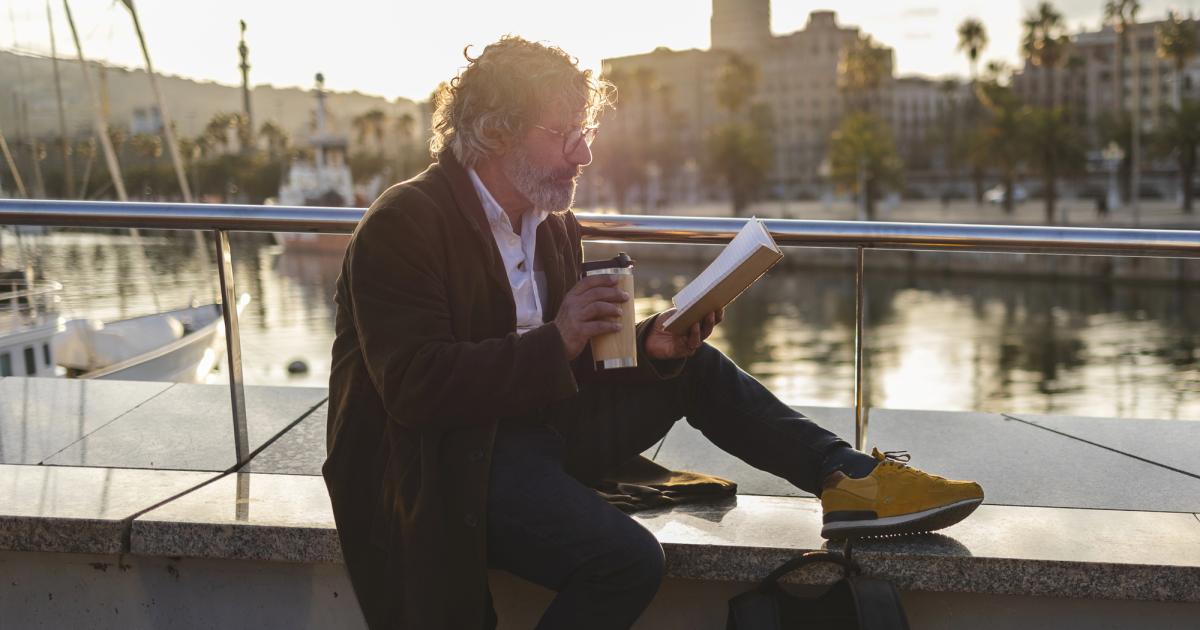 professor on sabbatical reading a book near water