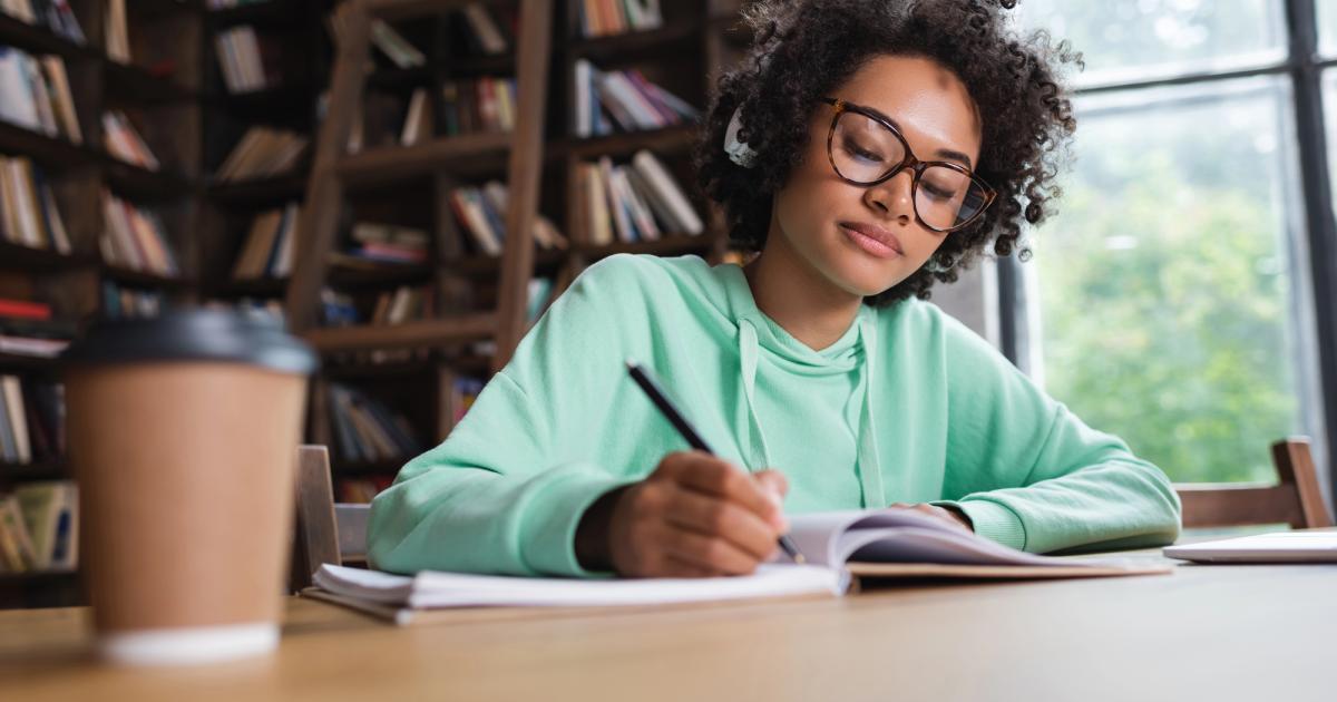 student writing application on laptop in library